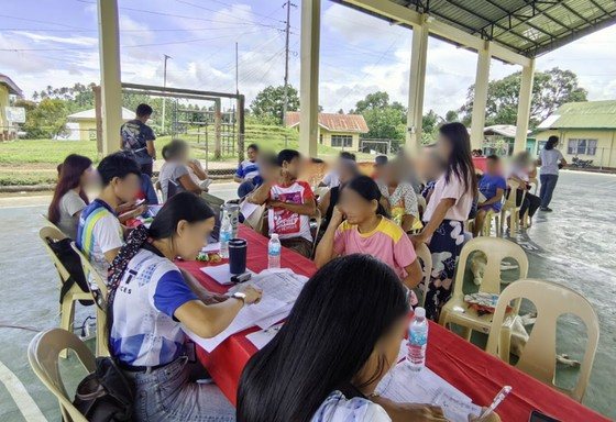 Residents registering at tables in an open-air covered court